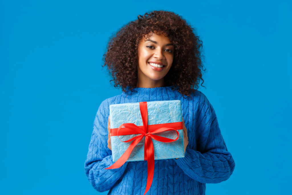 Black woman in sweater with gift in hand